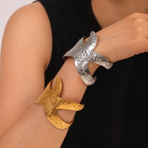 Close-up of gold and silver starfish bracelets with hammered texture on a model's wrist