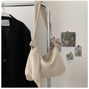 Detailed close-up of a beige crescent bag with knotted strap and silver chain accent