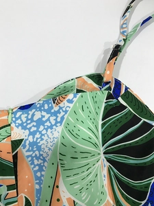 Close-up of tropical leaf print jumpsuit showing adjustable strap and hidden side zipper