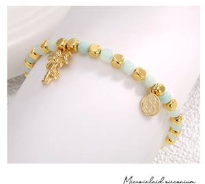 Macro detail of beaded bracelet with gold palm tree charm and turquoise stone beads
