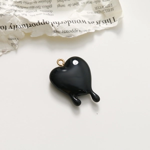 Nahaufnahme eines schwarzen schmelzenden Herzanhängers mit Goldring für DIY-Schmuck