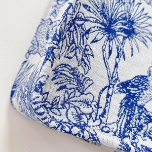 Close-up of blue and white Toile de Jouy woven fabric with intricate floral embroidery
