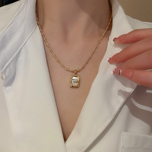 Detail einer vergoldeten Halskette mit rechteckigem Perlmuttanhänger im Vintage-Stil