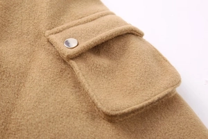 Detailed macro view of camel wool jacket fabric with flap pocket and silver metal button