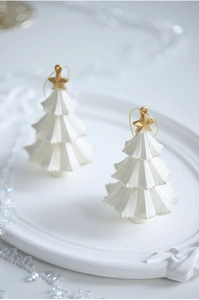 Close-up of mini white ceramic Christmas tree ornaments with gold stars on a tray