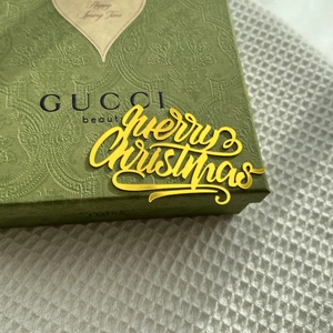 Close-up of green Paisley gift box with golden Merry Christmas 3D lettering