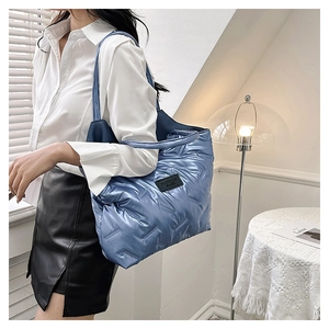 Close-up of quilted blue tote bag with metallic luster and fashion label detail