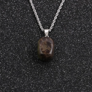 Detail of amethyst quartz pendant on silver twist chain over a black glittering background