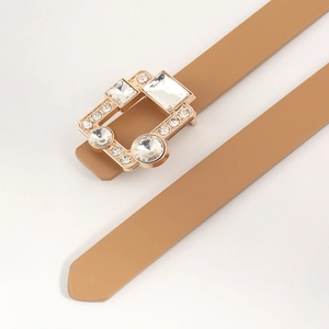 Detail of luxury thin camel PU leather belt with crystal-encrusted gold buckle