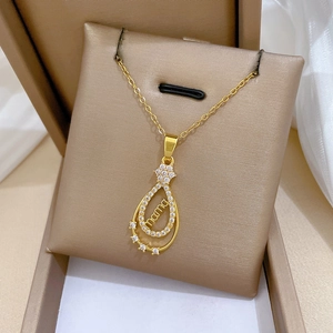 Détail du pendentif MAMA en forme de goutte doré avec zircons en écrin de velours