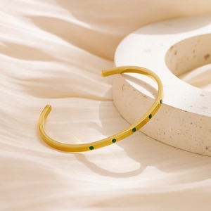 Detail of 18k gold plated stainless steel cuff featuring five green round gemstones