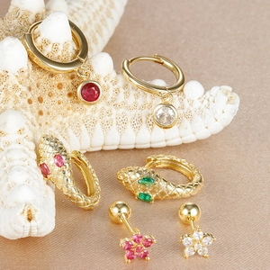 Detail of luxury snake earrings and zircon floral studs on champagne silk background