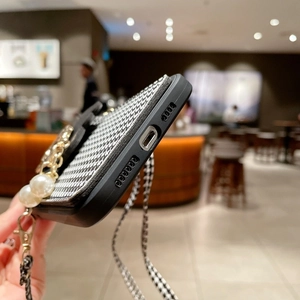 Detail of iPhone case with houndstooth pattern, pearl gold chain, and precision cutouts