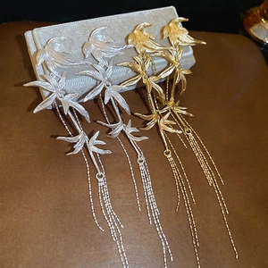Bamboo leaf tassel earrings in gold and silver finish on luxury jewelry box display