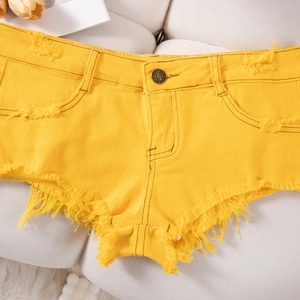 Dettaglio di pantaloncini di jeans gialli con orli sfrangiati e trama strappata usata