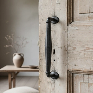 Vintage industrial black cast iron door handle mounted on an antique weathered wooden door