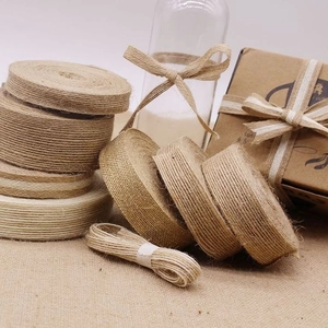 Detailed texture of natural jute ribbon rolls with white edge stitching for DIY gift crafts