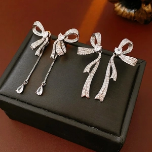 Elegant silver bow earrings with zircon tassels and pear-shaped pendants on black leather
