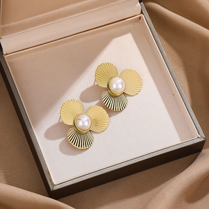 Gold clover earrings with white pearls in a jewelry box on brown satin background