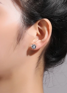 Vue macro d'une boucle d'oreille couronne plaquée or 18K portée sur l'oreille