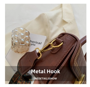 Detail of vintage brown leather bag with golden hardware and colorful fabric strap