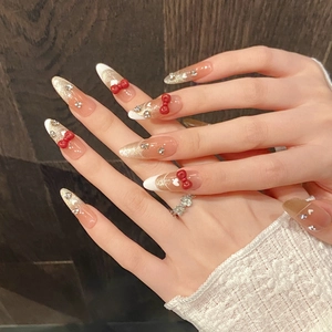 Unghie finte a mandorla fatte a mano con French tips bianche, fiocchi 3D rossi e cuori