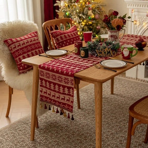 Red Christmas table runner with snowflake and reindeer patterns and decorative tassels