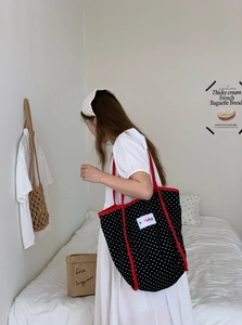 Detail of a large black polka dot tote bag with red trim and a FUTURE letter patch