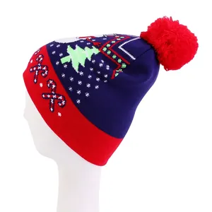Detail of knit Christmas hat featuring festive tree patterns and a red fluffy pom-pom top