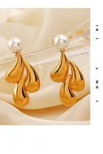 Detail shot of 18K gold plated teardrop earrings with white pearls on beige silk