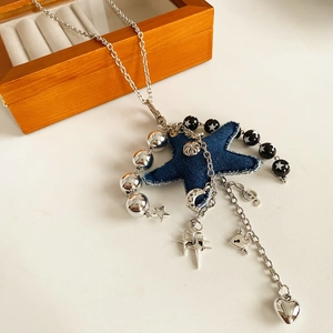 Detail view of denim star pendant necklace with silver charms and beads on white surface