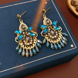 Macro shot of vintage gold drop earrings with blue crystal tassels on a starry jewelry box