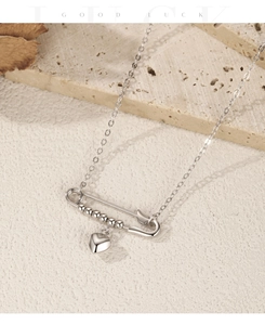 Detailed view of silver safety pin pendant with polished heart on fine link chain