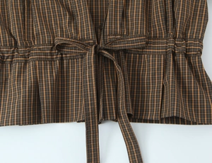 Detail view of plaid cotton shirt showing waist drawstring and tie design