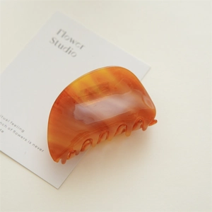 Detailed macro view of the glossy amber tortoiseshell texture on the large hair claw clip