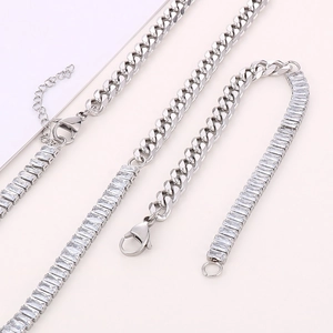 Silver Cuban chain necklace and zircon bracelet set on a soft pink background