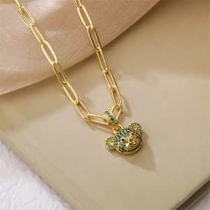 Macro detail of paperclip chain necklace with green zircon bear pendant in gold plating