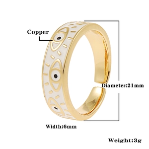 Detailed view of golden open ring featuring white enamel evil eye patterns and copper material
