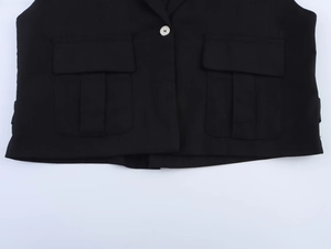 Détail du gilet noir en lin avec bouton blanc et grandes poches à rabat élégantes