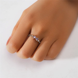 Detailed shot of bow-shaped silver ring with purple heart-shaped stones and tiny diamonds