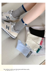Detail of ribbed knit mid-calf socks with colorful fabric patches and cartoon labels