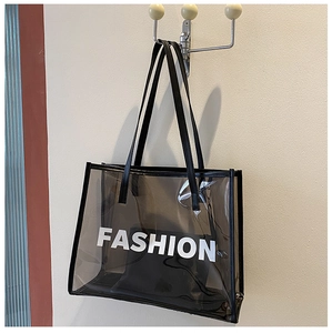 Detail of a large black semi-transparent PVC tote bag with white FASHION print on a hook