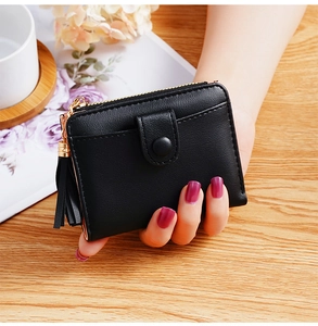 Close-up of black women's wallet with gold zipper and stylish tassel detail on wood background