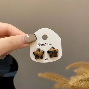 Detail showing star-shaped leopard print earrings with brown and black resin pattern
