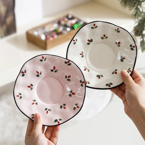 Detail of wavy edge ceramic plates featuring hand-painted red strawberries and black trim