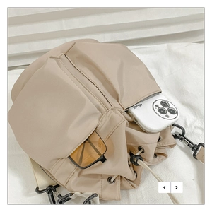 Detail of khaki nylon crossbody bag showing drawstring pockets and storage capacity
