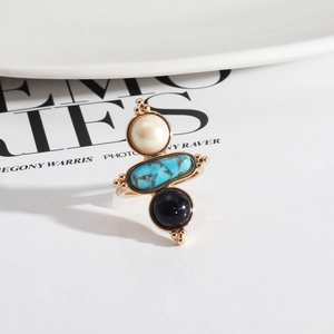 Vintage golden ring with three stacked natural stones on a white ceramic plate