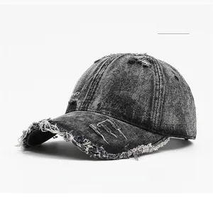 Macro detail of washed black denim baseball cap showing distressed raw edges and frayed holes