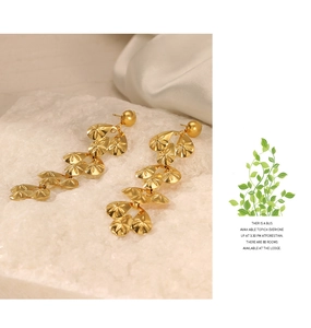Close-up of golden multi-layer teardrop earrings with engraved radial star patterns