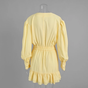 Detail of lantern sleeves with button cuffs and ruffled hem on a yellow mini dress